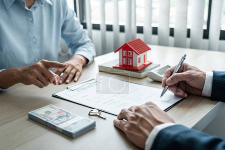 Photo for Real estate broker agent consulting the customer to a decision making sign insurance form contract, home model mortgage loan offer for and house insurance. - Royalty Free Image