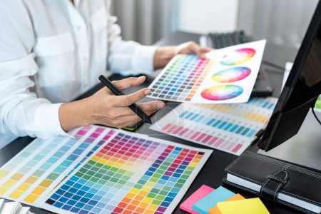 Junge kreative Grafikdesignerin arbeitet an Farbauswahl und Zeichnung auf dem Grafiktablett am Arbeitsplatz, Farbmusterdiagramm für Auswahlfärbung als Inspiration für die Schaffung einer neuen Kollektion