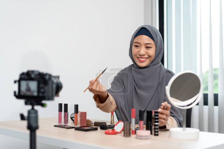 Photo for Woman muslim blogger is present make up tutorial beauty cosmetic review product and broadcast live streaming video to teaching online on the camera screen at office studio. - Royalty Free Image