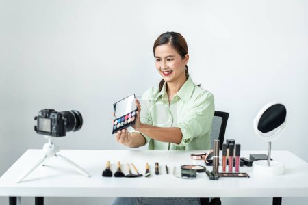 Photo for Woman blogger is present make up tutorial beauty cosmetic review product and broadcast live streaming video to teaching online on the camera screen at office studio. - Royalty Free Image