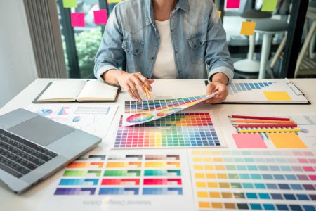 Photo for Young creative graphic designer working on color selection and drawing on graphics tablet at workplace, Color swatch samples chart for selection coloring in inspiration to create new collection. - Royalty Free Image