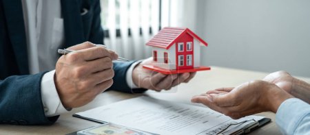 Immobilienmakler Makler hält Hausmodell und sendet an den Kunden nach Unterzeichnung Mietvertrag des Kaufvertrages.
