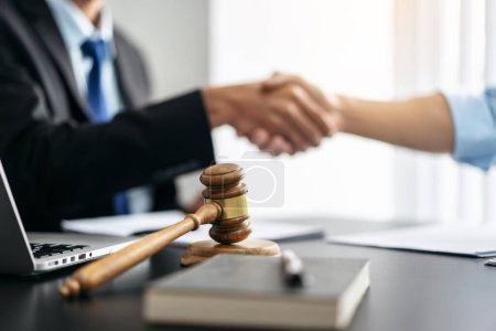Photo for Handshake after good cooperation, Two people shaking hands after discussing contract agreement on front a judge's gavel. - Royalty Free Image