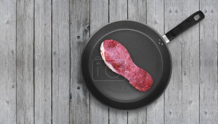 Photo for Cut of meat in the shape of shoe sole on pan. Poor quality meat concept. Tough meat. Overhead shot. - Royalty Free Image