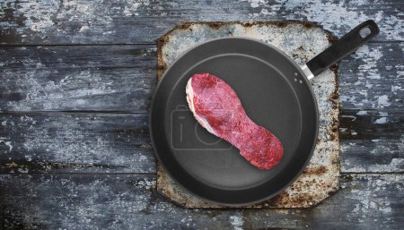 Photo for Cut of meat in the shape of shoe sole on pan. Poor quality meat concept. Tough meat. Overhead shot. - Royalty Free Image