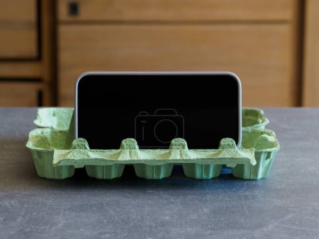 Foto de Soporte para smartphone DIY fabricado en cartón de huevo. Receta para cocinar. Hackeos de cocina - Imagen libre de derechos