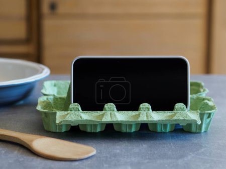 Foto de Soporte para smartphone DIY fabricado en cartón de huevo. Receta para cocinar. Hackeos de cocina - Imagen libre de derechos