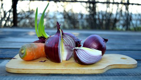 Téléchargez les photos : Still life with purple onions and carrots on a cutting board for vegetables - en image libre de droit