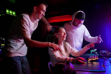 Gesellschaft fröhlicher junger Leute in einem Computerclub blickt auf den Monitor und lacht, Spieler kommunizieren und freuen sich gemeinsam