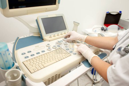 Téléchargez les photos : Doctor's hands use a modern ultrasound machine and press the keys of medical equipment, close-up - en image libre de droit