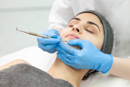 Téléchargez les photos : Female cosmetologist makes mechanical cleaning of the skin of the face of girl in cosmetology clinic, professional peeling of the skin of the face, close-up of skin care - en image libre de droit