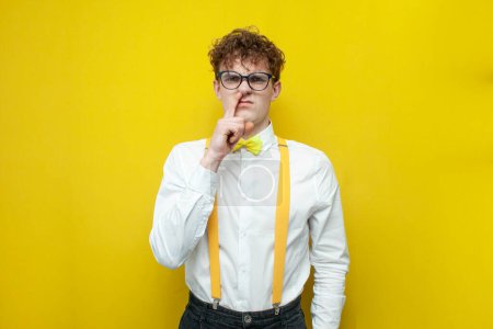 Photo for Young uncultured guy in festive outfit picks his nose, nerd student in shirt with bow tie and suspenders is not well-mannered and vile - Royalty Free Image