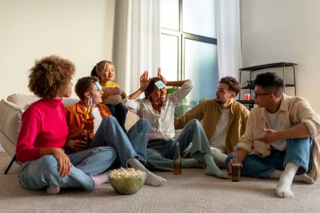 Photo for Multiracial group of young friends playing charades drinking beer and having fun at home, students sitting on the sofa and pretending to be different animals and drinking alcohol together in the room - Royalty Free Image