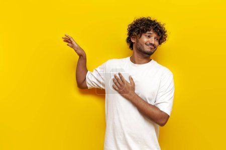 Téléchargez les photos : Jeune indien insouciant gars refusant et évitant sur fond jaune isolé, homme sud-asiatique en t-shirt blanc agitant et ignorant - en image libre de droit