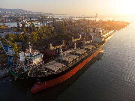 Luftaufnahme eines großen Frachtschiffs Massengutfrachter wird im Hafen bei Sonnenuntergang mit Weizenkorn beladen