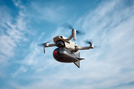Téléchargez les photos : Drone civil grand public avec une grosse bombe en plastique à bord vole dans le ciel bleu - en image libre de droit