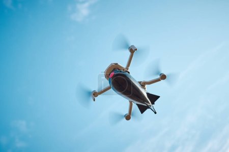 Photo for Drone with a bomb for fishing on board flies in the blue sky - Royalty Free Image