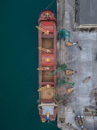 Photo for Aerial view of big cargo ship bulk carrier is loaded with grain of wheat in port, vertical shoot - Royalty Free Image