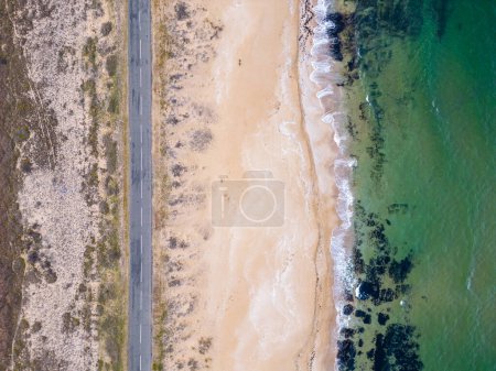 Aerial View of the road along the sea sandy coast. cars drive on the road along the sea