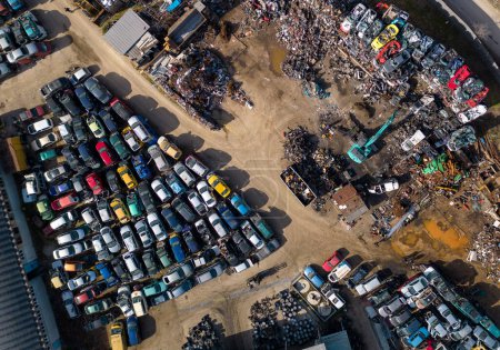Foto de Vista aérea de un vertedero de coches, donde una máquina se ve separando los coches viejos en chatarra. La colección masiva de coches abandonados y la maquinaria pesada utilizada para procesarlos son visibles desde arriba. - Imagen libre de derechos