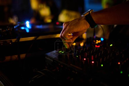 Téléchargez les photos : Un gros plan des DJ main sur la console de mixage dans une boîte de nuit, l'artisanat de la musique et de l'ambiance de danse. - en image libre de droit