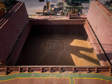 Photo for Aerial top close-up view of a bustling seaport, where a massive cargo ship, a bulk carrier, is being loaded with wheat grains - Royalty Free Image