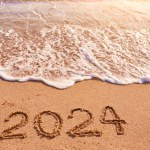 2024 year drawing on sandy beach sea at sunny day