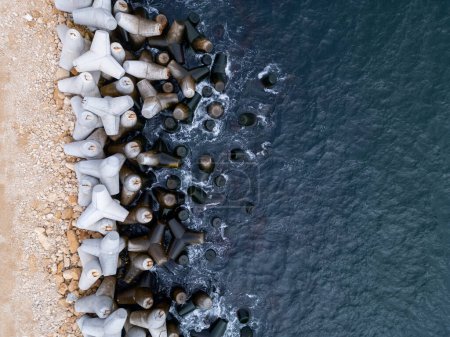 Une rangée de cylindres en béton placés sur une plage de sable.