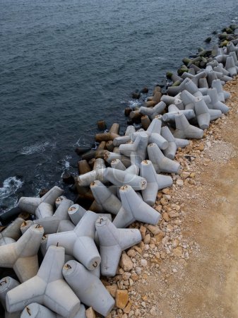 A row of concrete cylinders placed on a sandy beach.