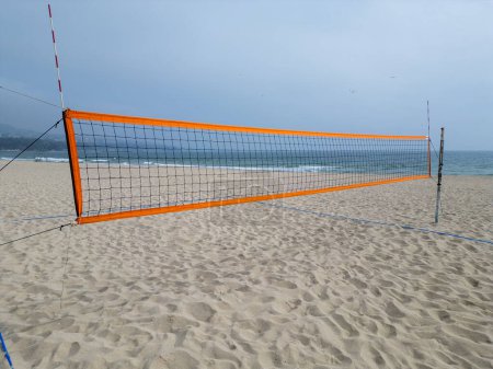 Photo for A volleyball net set up on a sandy beach near the ocean, ready for a game under the sunny sky. - Royalty Free Image