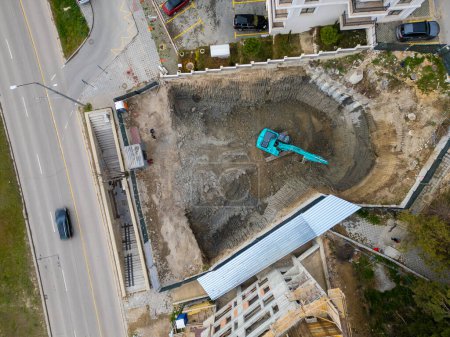 Una excavadora está cavando un hoyo para la construcción de otro edificio en el centro de la ciudad, vista aérea.