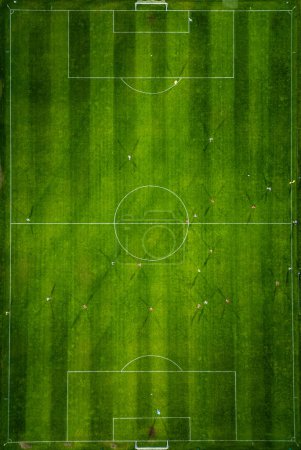 Vue aérienne d'un terrain de soccer en action, où les joueurs courent, passent et marquent des buts