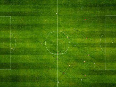 Aerial view of a soccer field in action, with players running, passing, and scoring goals