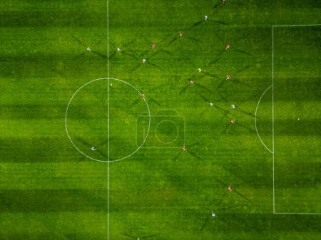 Vista aérea de un campo de fútbol en acción, con jugadores corriendo, pasando y anotando goles