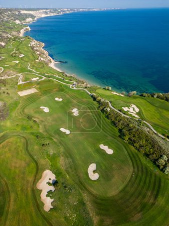 Overhead view of a golf course set against the backdrop of the ocean, showcasing the green fairways and blue waters.