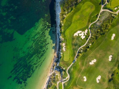 Una vista de alto ángulo de un campo de golf situado en el fondo del océano, que muestra exuberantes calles verdes y trampas de arena.