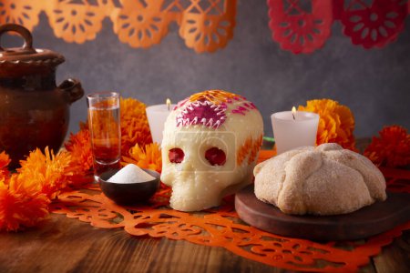 Foto de Pan de Muerto con cráneo de azúcar y flores de Cempasuchil o Caléndula y Papel Picado. Decoración tradicionalmente utilizada en altares para la celebración del día de los muertos en México - Imagen libre de derechos