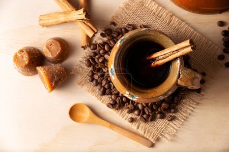Auténtico café mexicano casero (café de olla) servido en taza de arcilla tradicional hecha a mano (Jarrito de barro) sobre mesa de madera rústica.