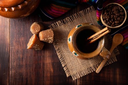 Photo for Authentic homemade mexican coffee (cafe de olla) served in traditional handmade clay mug (Jarrito de barro) on rustic wooden table. - Royalty Free Image