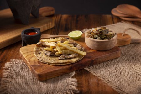 Rindersteak Taco mit Pommes frites. Sehr beliebter Taco in Mexiko, genannt Taco de Bistec oder Carne Asada, hausgemachtes Roastbeef, serviert auf einer Maistortilla. Mexikanisches Streetfood.