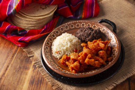 Chicharron en salsa roja. Schweinefleisch in roter Sauce mit Reis und gebackenen Bohnen. Traditionelles hausgemachtes Gericht sehr beliebt in Mexiko, dieses Gericht ist Teil der beliebten Tacos de Guisado.
