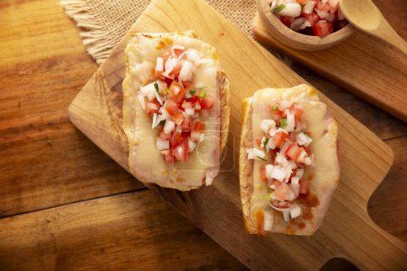 Photo for Molletes. Mexican recipe based on bolillo bread split lengthwise, spread with refried beans and gratin cheese, adding pico de gallo sauce and some protein such as ham, bacon or chorizo. - Royalty Free Image
