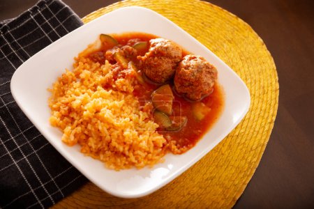 Frikadellen mit rotem Reis. In Mexiko sind sie als Albondigas bekannt, die mit Gemüse in einer leichten Tomatensoße namens Caldillo serviert werden. Sehr beliebtes Rezept für hausgemachtes Essen in Mexiko.