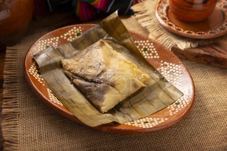 Photo for Oaxacan Tamale. Prehispanic dish typical of Mexico and some Latin American countries. Corn dough wrapped in banana leaves. The tamales are steamed. - Royalty Free Image