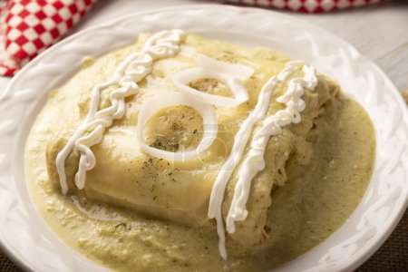 Photo for Mexican food. Enchiladas with creamy green sauce filled with shredded chicken meat and covered with melted cheese, in Mexico they are called Swiss Enchiladas. Very popular recipe in Mexican cuisine. - Royalty Free Image