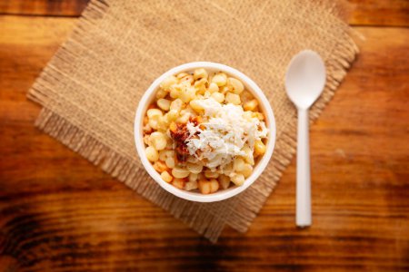 Photo for Esquites. Corn kernels cooked and served with mayo, sour cream, lemon and chili powder, very popular street food in Mexico, also known as Elote en Vaso. The recipe varies depending on the region. - Royalty Free Image