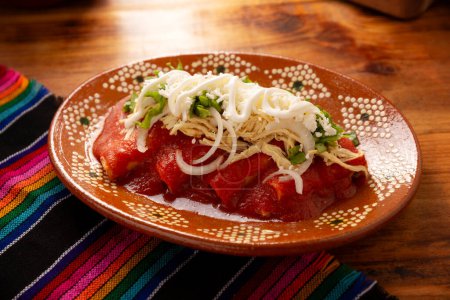Photo for Entomatadas. Also known as Enjitomatadas, a typical dish of Mexican cuisine prepared with corn tortilla, tomato sauce and stuffed with shredded chicken meat. Classic homemade recipe. - Royalty Free Image