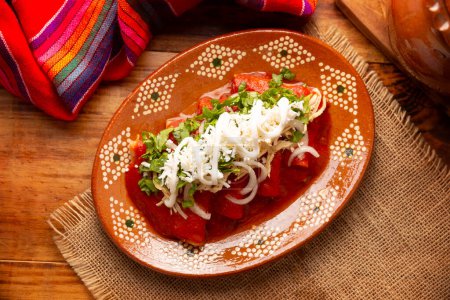 Photo for Entomatadas. Also known as Enjitomatadas, a typical dish of Mexican cuisine prepared with corn tortilla, tomato sauce and stuffed with shredded chicken meat. Classic homemade recipe. - Royalty Free Image