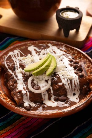 Enfrijoladas. Tortillas de maíz sumergidas en salsa de frijoles, cubiertas de crema y queso, se pueden cubrir o rellenar con carne de pollo, queso o algún otro ingrediente. Plato tradicional mexicano.