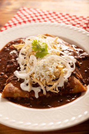 Enfrijoladas. Tortillas de maíz sumergidas en salsa de frijoles, cubiertas de crema y queso, se pueden cubrir o rellenar con carne de pollo, queso o algún otro ingrediente. Plato tradicional mexicano.